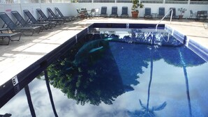 A swimming pool with lounge chairs and a table.