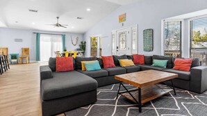 A modern living room with a sectional sofa, colorful cushions, a wooden coffee table, and a patterned rug.