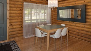 A wooden cabin interior with a dining table, chairs, a chandelier, and a mirror.