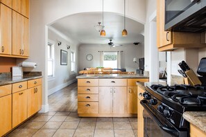 A kitchen with wooden cabinets, a central island, a stove, and pendant lighting.