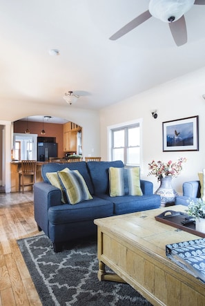 A living room with a blue sofa, wooden coffee table, and a rug.