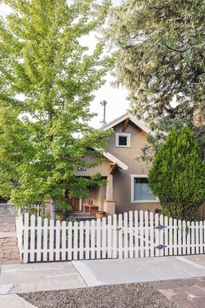Une maison d’habitation avec une clôture en bois peinte en blanc, une cheminée et une petite fenêtre.