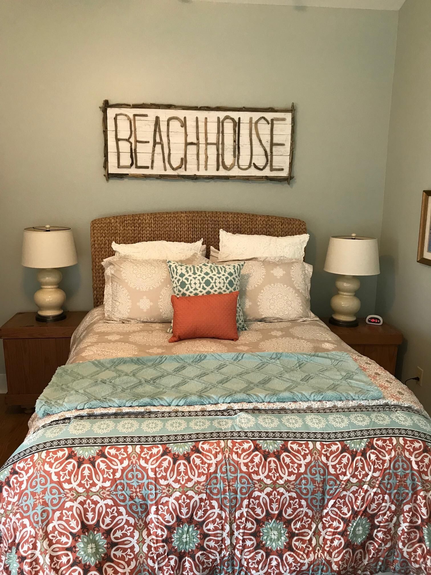 Une chambre à coucher avec un lit, deux tables de chevet et un panneau mural sur lequel on peut lire « BEACHHOUSE ».