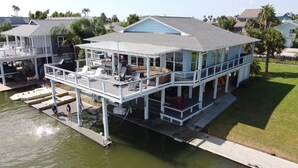 Une maison située au bord de l’eau, dotée d’une terrasse couverte, d’une piscine et d’un quai pour bateaux.