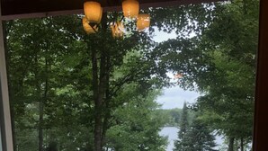 A patio with a table and chairs, a hanging light fixture, and a view of trees through a screen door. - Summer is coming!   (Longville)