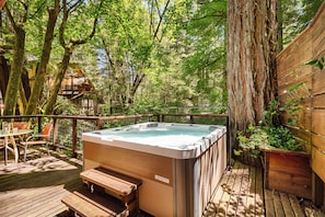 A hot tub on a wooden deck surrounded by trees.