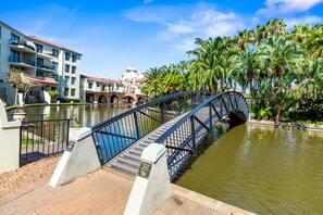 A bridge over a canal with buildings and palm trees in the background. - Capri 101 (Cape Town)