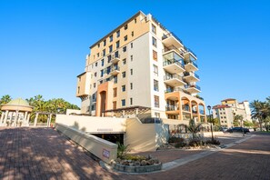 A multi-story hotel with balconies, a covered entrance, and a landscaped area with palm trees. - Capri 101 (Cape Town)