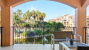 A balcony with a view of a water body, palm trees, and buildings in the background. - Capri 101 (Cape Town)