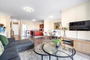 A modern living room with a sofa, a glass coffee table, and a flat-screen TV. - Capri 101 (Cape Town)