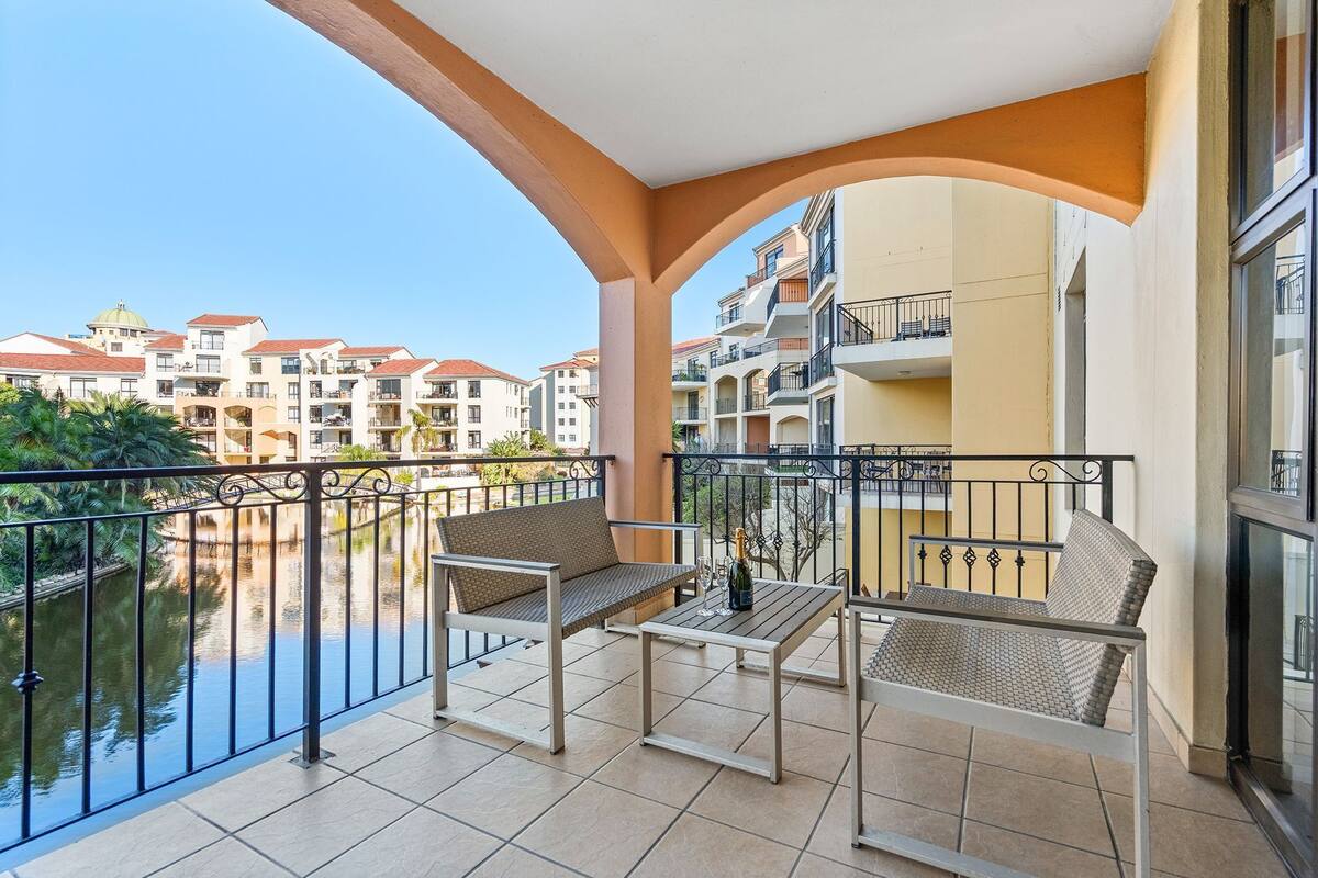 A balcony with a table, two chairs, and a bottle of champagne.