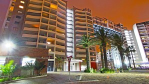 A multi-story hotel with balconies, a brick facade, and palm trees in the foreground. - Knightsbridge 407 (Cape Town)