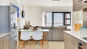 Una cocina moderna con zona de comedor, sofá y un amplio ventanal.