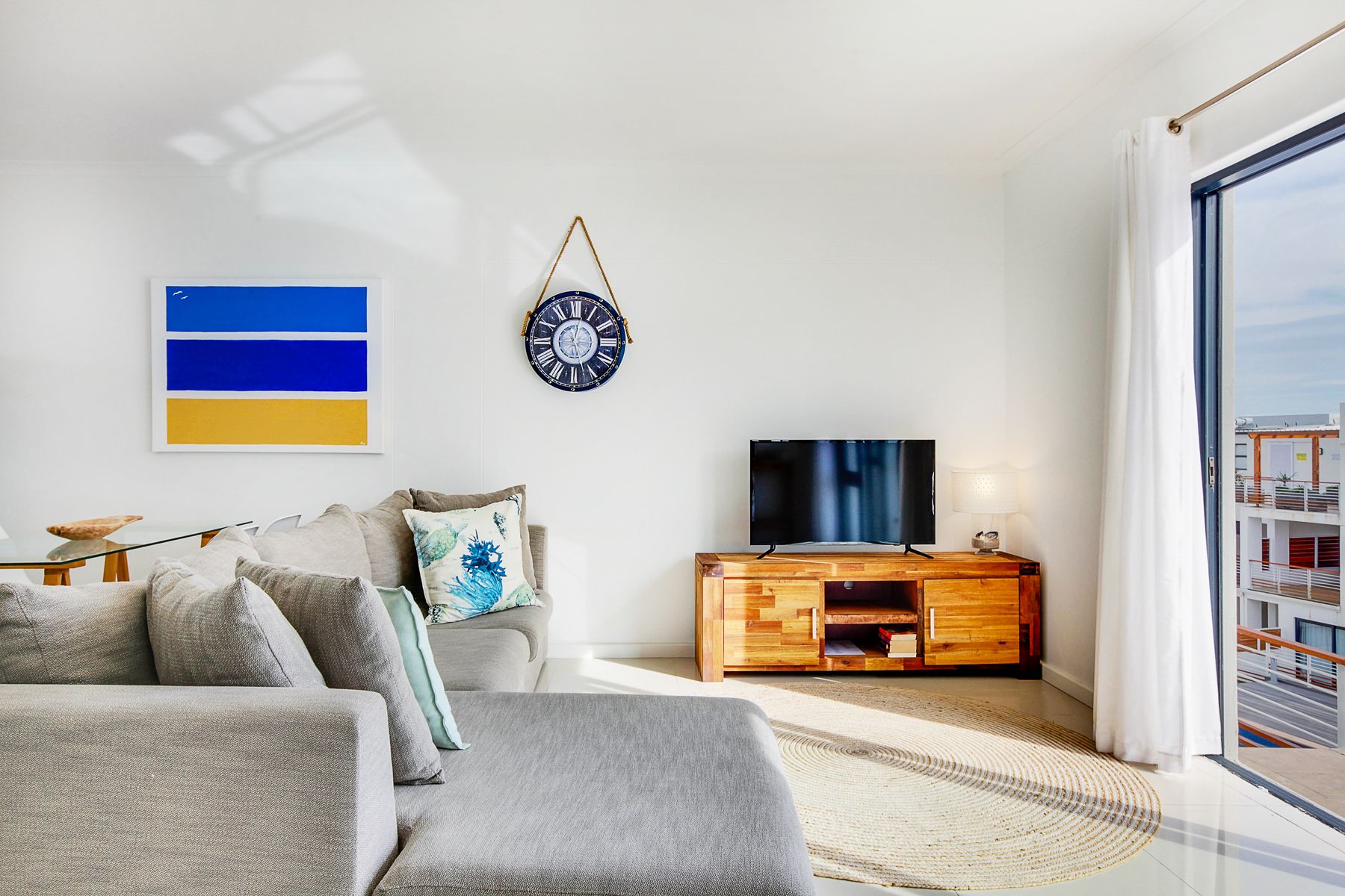 Ein modernes Wohnzimmer mit einer Couch, einem Fernseher und einem Holzschrank.