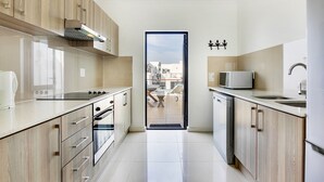 Una cocina moderna con armarios de madera, horno empotrado, microondas y pileta.