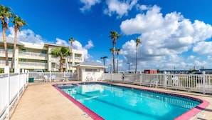 A swimming pool with a red edge, surrounded by palm trees and a white fence. - Studio 6 Corpus Christi, TX - North (Corpus Christi)