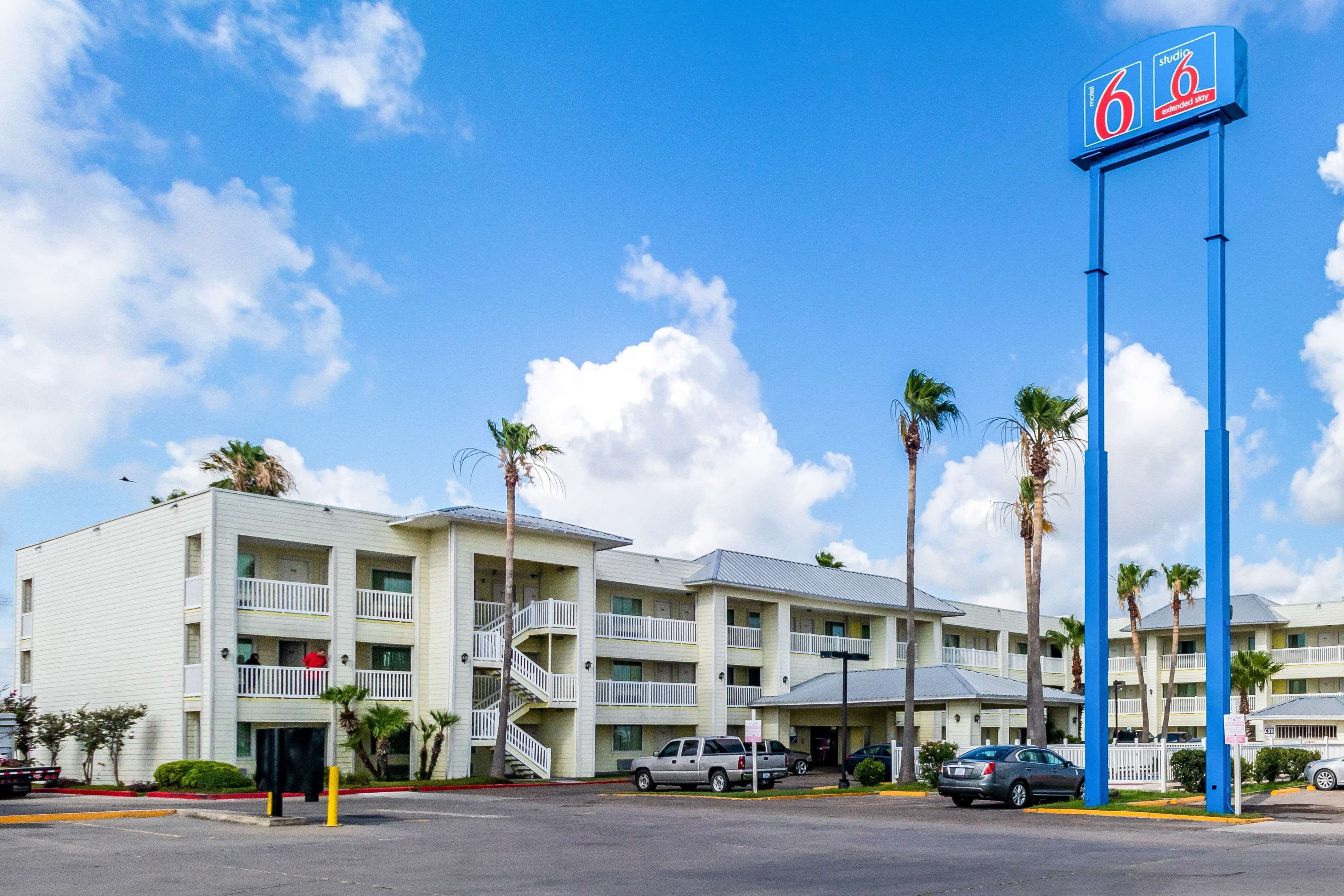 Un motel composé d’un bâtiment à deux étages, doté de nombreux balcons, et d’un parking où sont stationnés plusieurs véhicules.