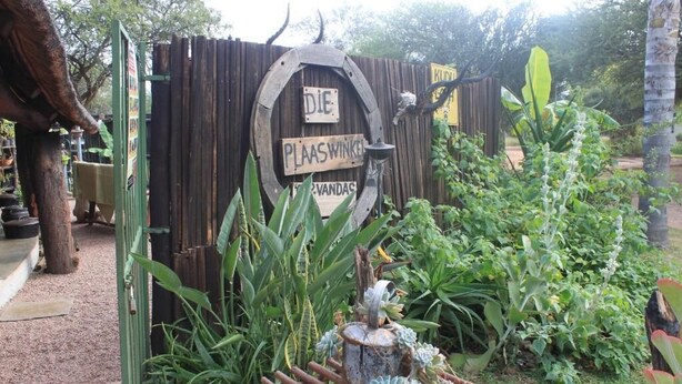 A garden entrance with a wooden sign that reads "DIE PLAASWINKE" and "WANDAS". - Grootgeluk Bush Camp (Mookgopong)
