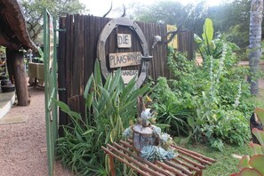 A garden entrance with a wooden sign that reads "DIE PLAASWINKE" and "WANDAS". - Grootgeluk Bush Camp (Mookgopong)