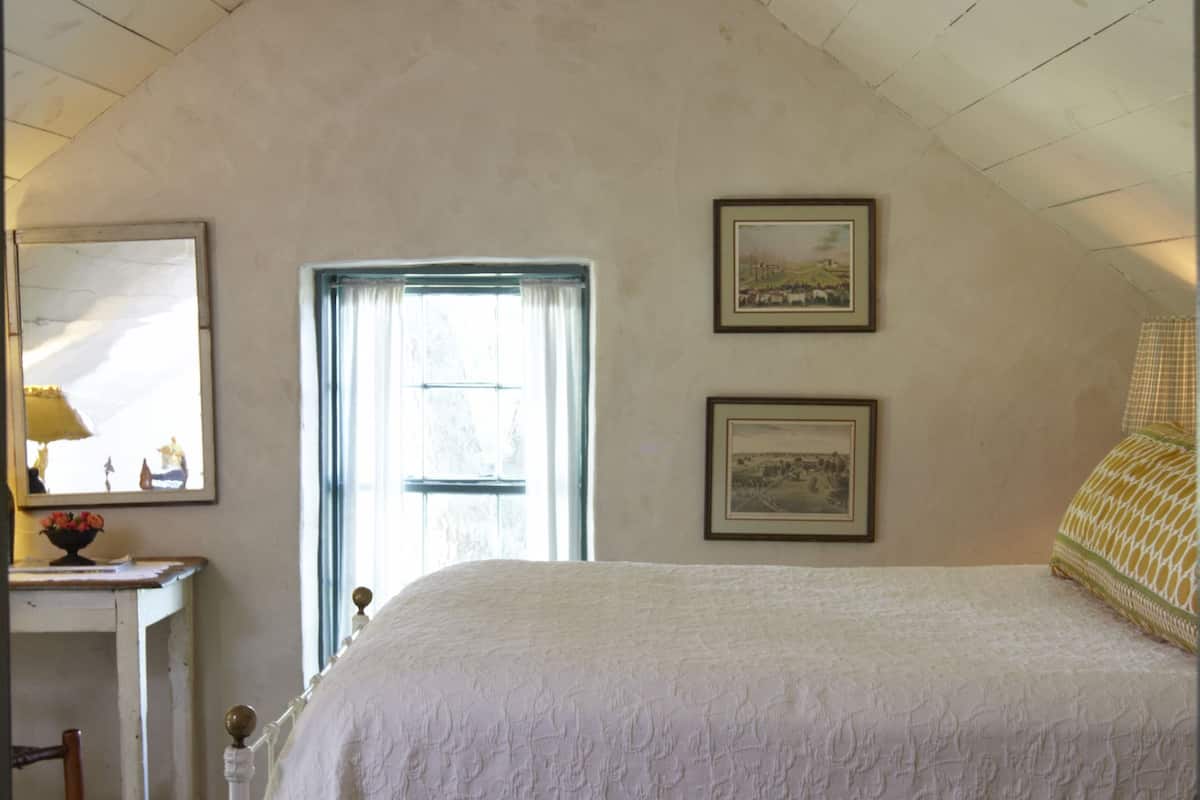 A bedroom with a bed, a desk, and two framed pictures on the wall.
