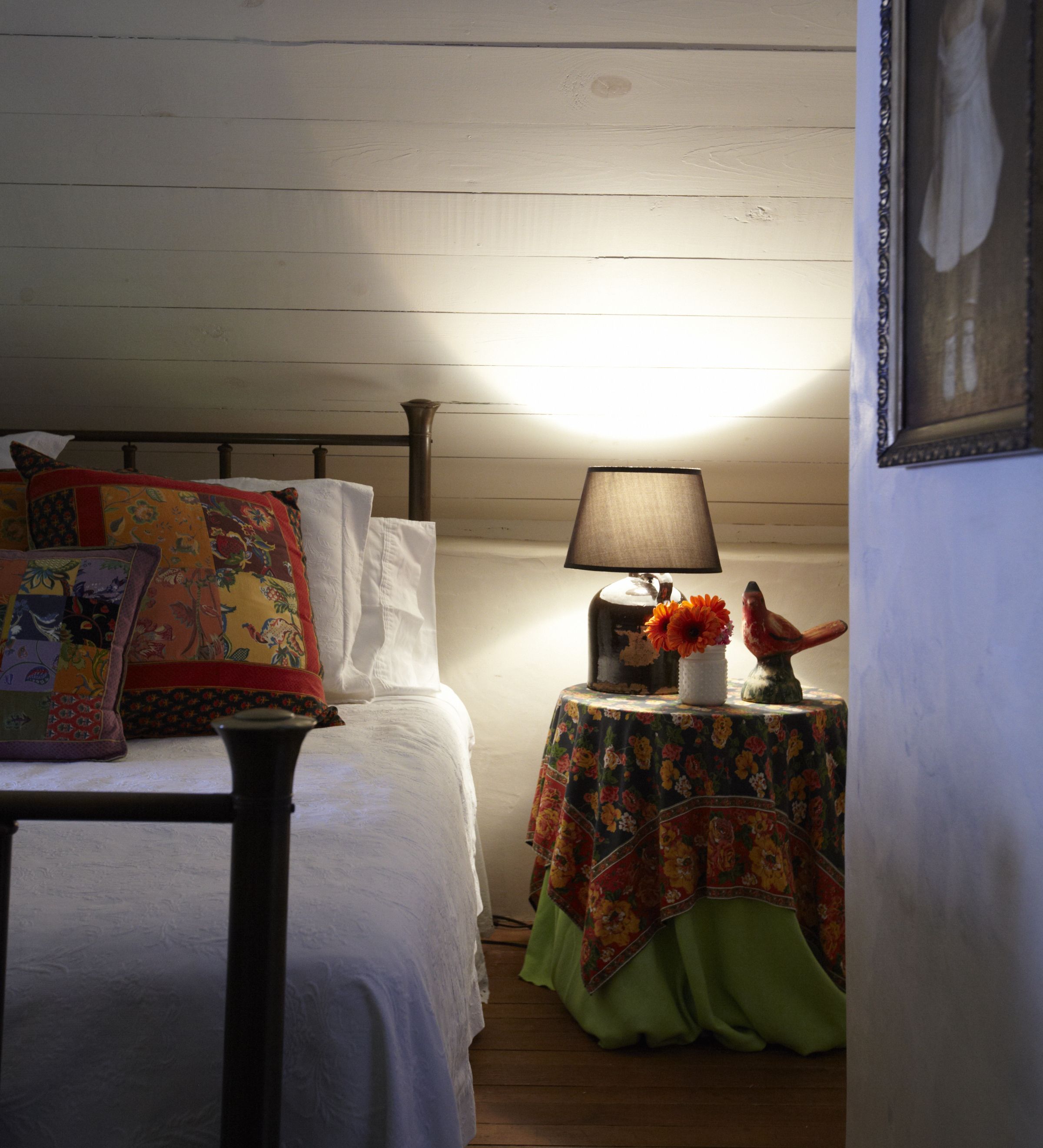 A bedroom with a bed, a nightstand, a lamp, and a framed picture on the wall.