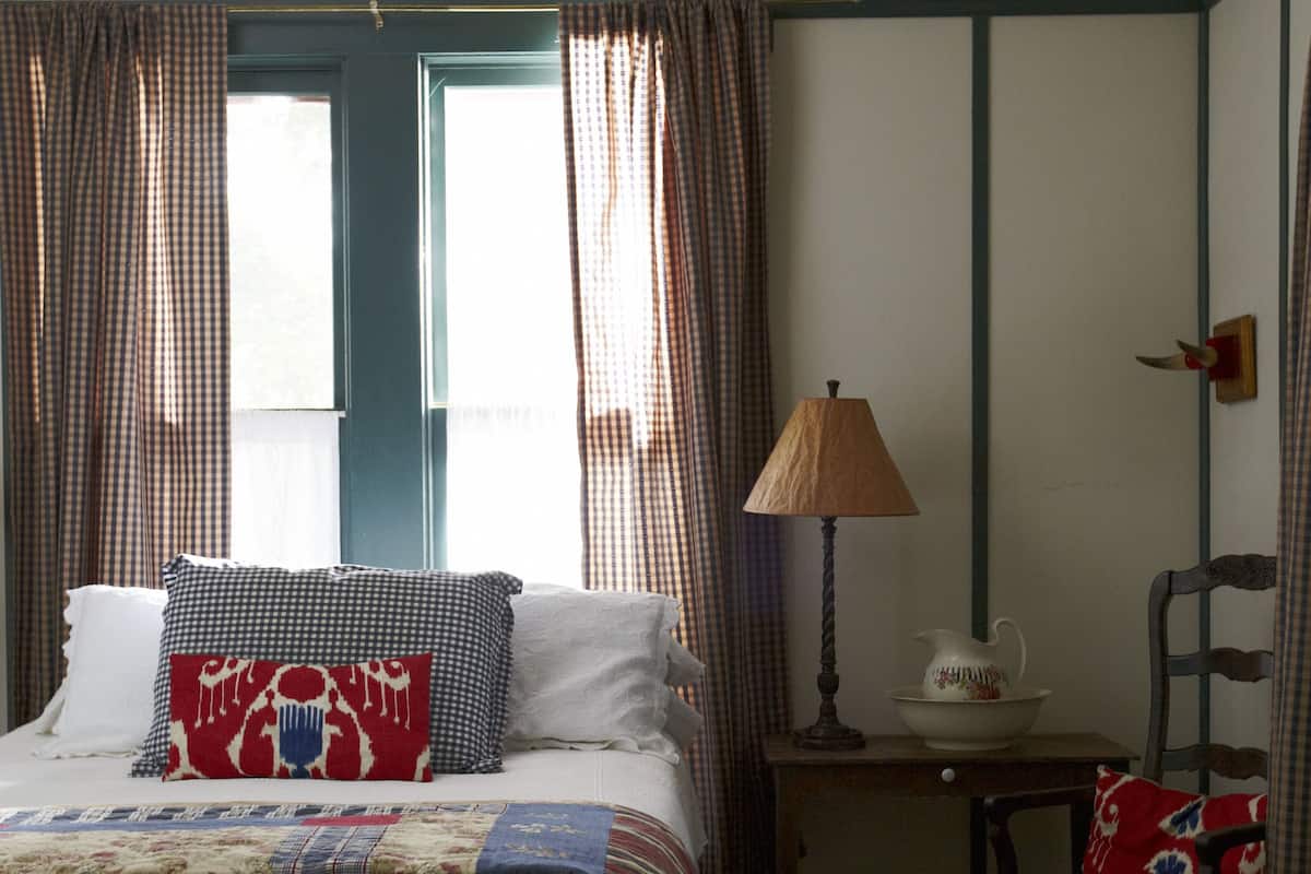 A bedroom with a bed, a chair, a lamp, and curtains.