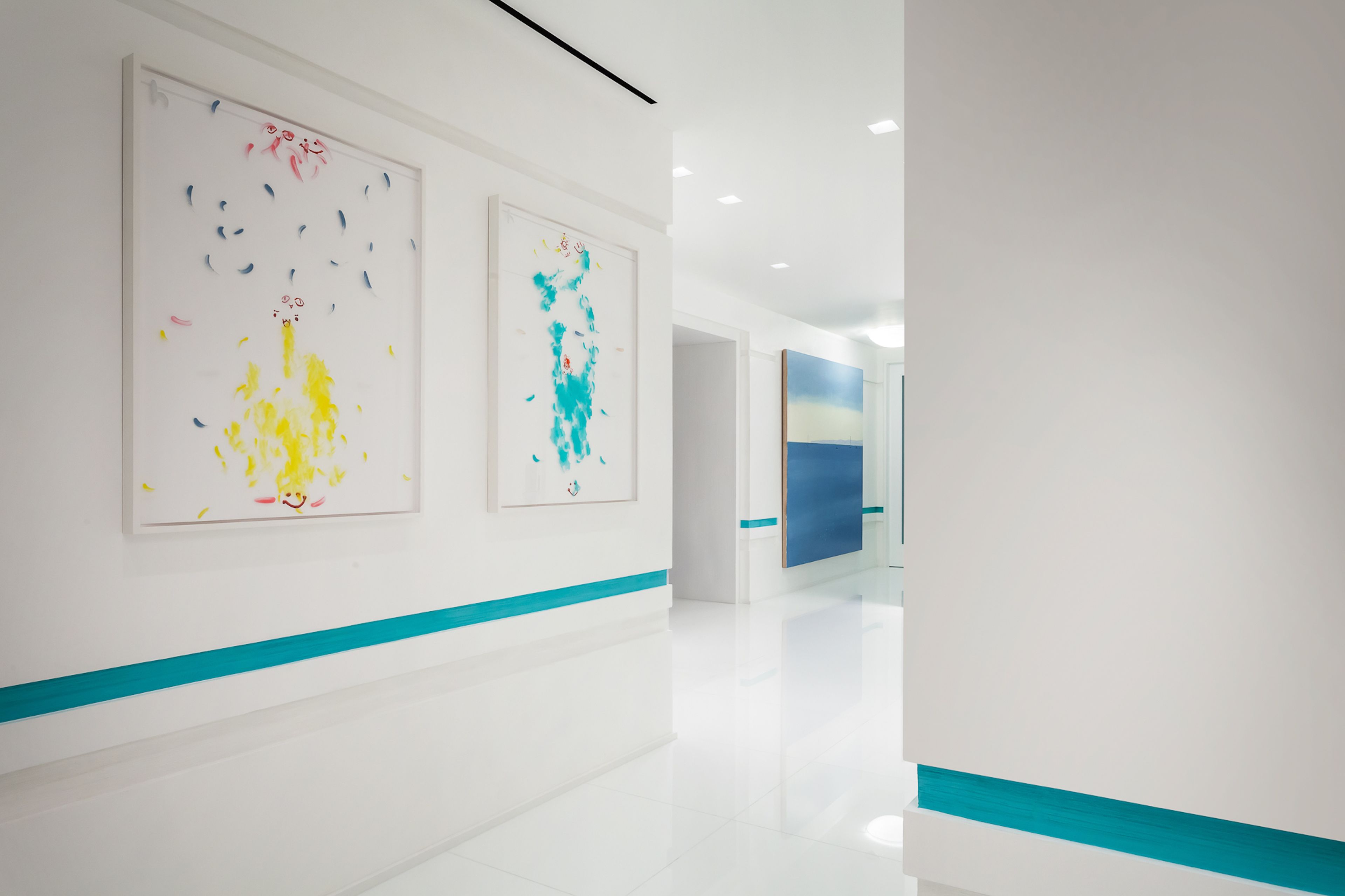 A modern hallway with white walls and a blue stripe at the bottom. There are two large abstract paintings on the walls.