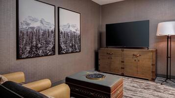 A living room with a sofa, a television on a wooden cabinet, and two framed pictures on the wall.