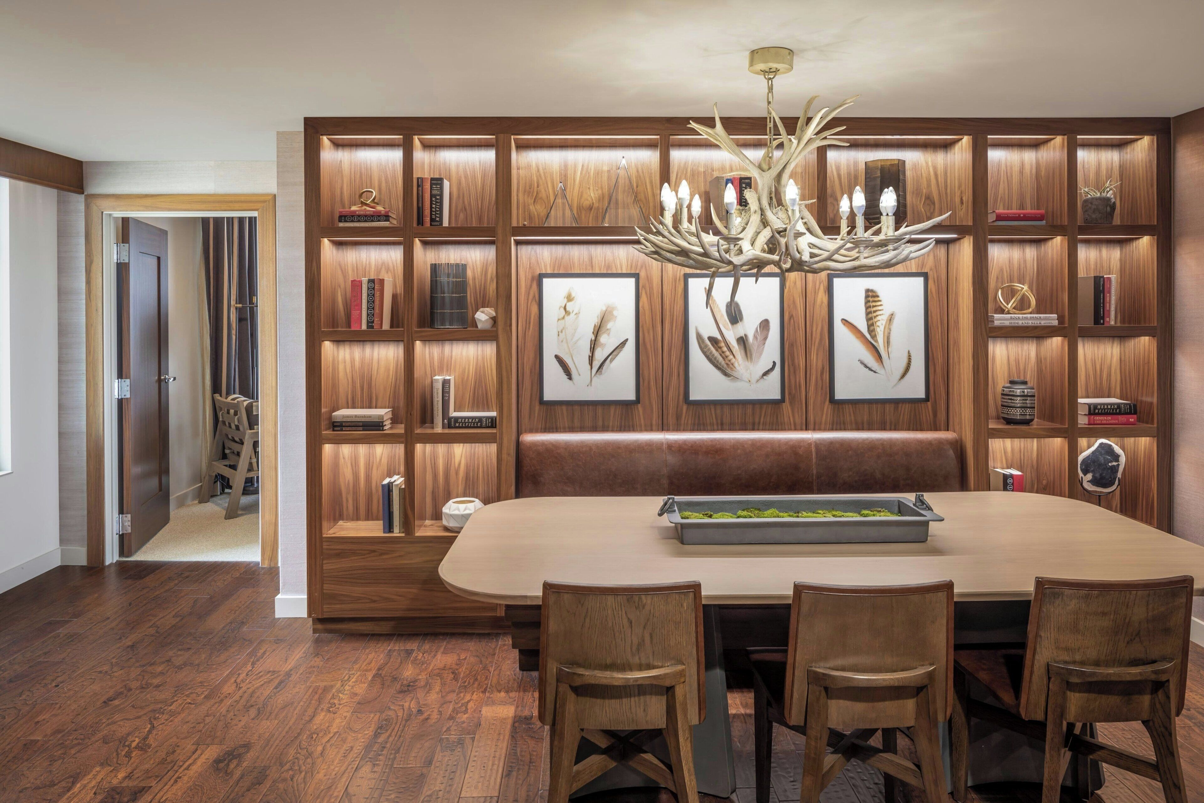 Un comedor con una mesa y sillas de madera, rodeado de paneles de madera y estantes con libros y objetos decorativos.