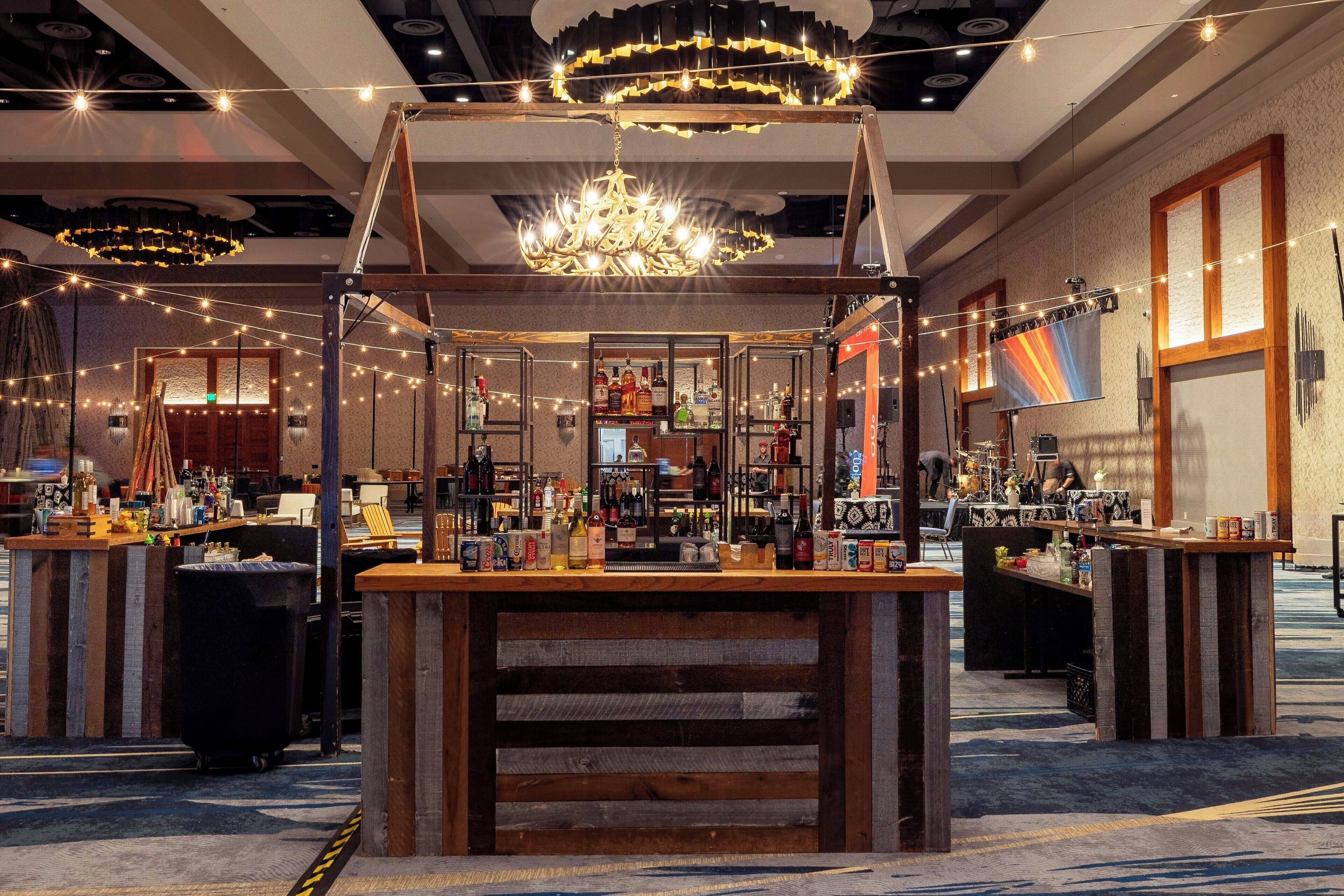Un espace bar avec des comptoirs en bois, un lustre et des guirlandes lumineuses.