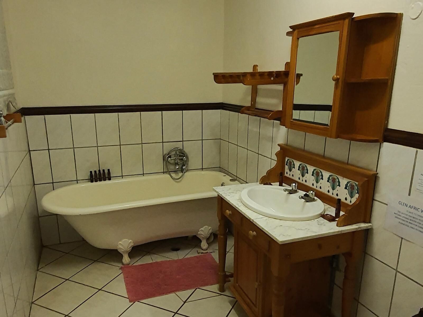A bathroom with a clawfoot bathtub, a wooden vanity with a mirror, and a tiled floor.