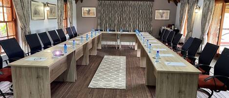 Un salón de conferencias con una larga mesa de madera, sillas negras y techo de techo de paja.