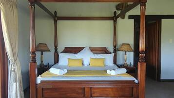 A four-poster bed with a wooden frame, white bedding, and two yellow pillows.
