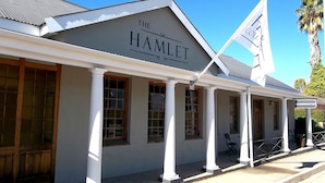 Un bâtiment sur lequel on peut lire l’inscription « The Hamlet ». Il est doté d’un porche couvert avec des colonnes blanches et de nombreuses fenêtres.