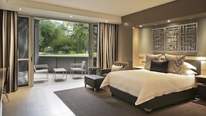 A modern bedroom with a large bed, a balcony with seating, and a view of greenery. - Kupferquelle Resort (Tsumeb)