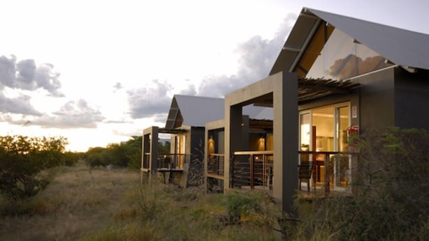 A modern building with large windows and a flat roof, surrounded by natural vegetation. - Kupferquelle Resort (Tsumeb)