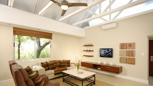 A modern living room with a sofa, armchair, coffee table, and a TV mounted on the wall. - Kupferquelle Resort (Tsumeb)
