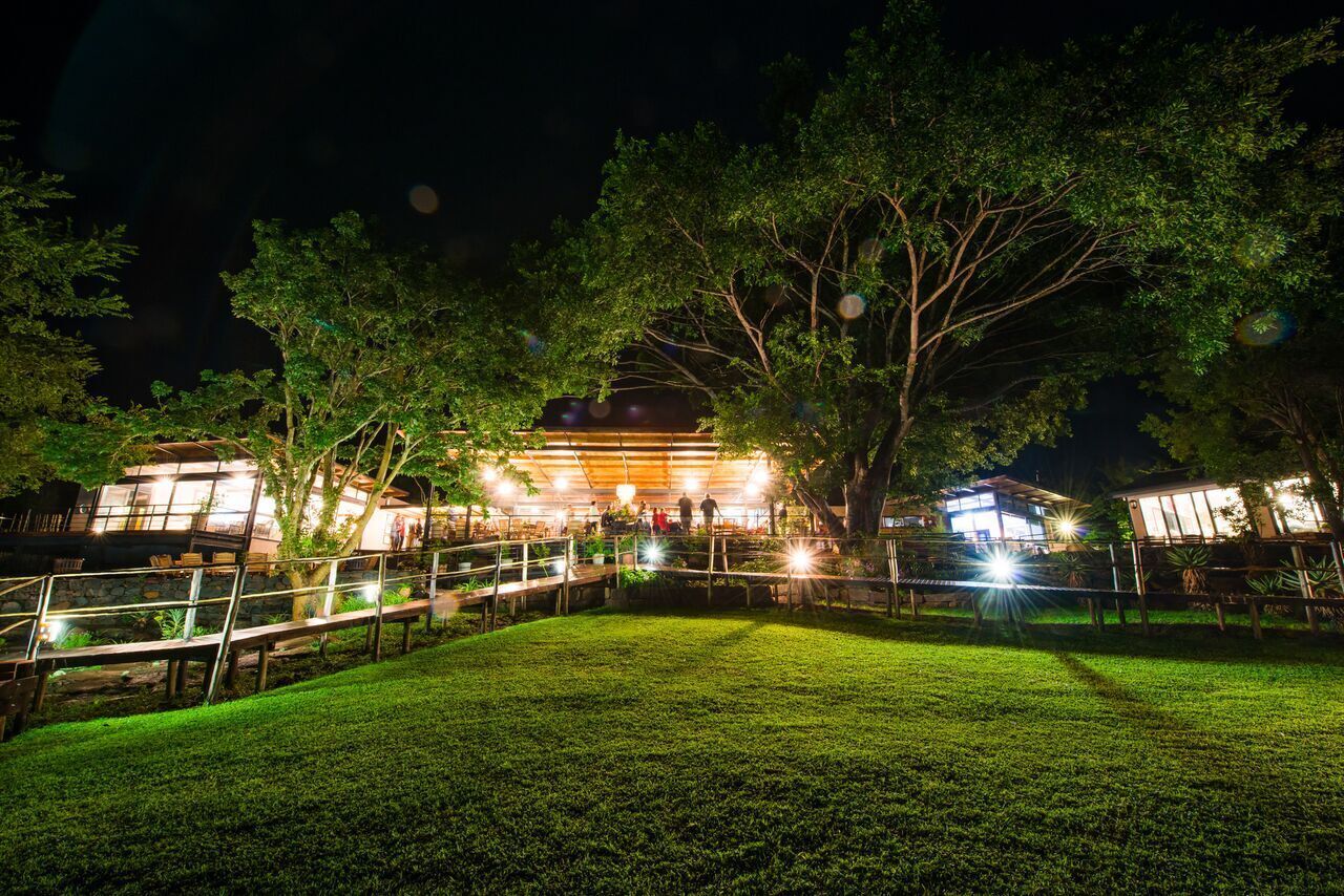 A well-lit outdoor area with a building, trees, and a grassy lawn.