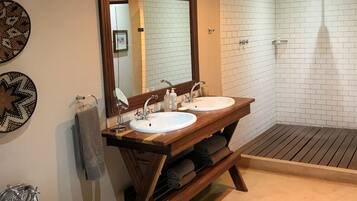 A bathroom with a freestanding bathtub, two sinks, a large mirror, and a shower area.