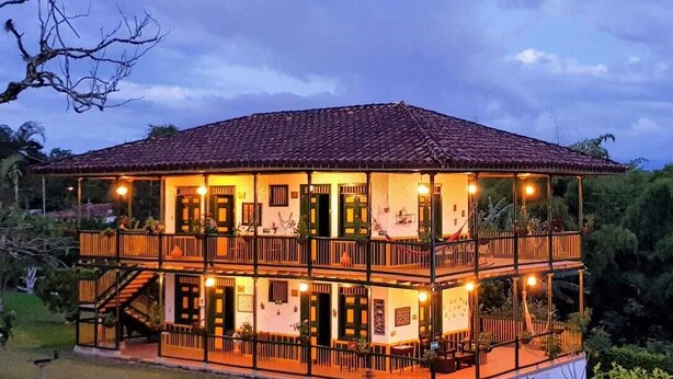A two-story building with a tiled roof, multiple balconies, and outdoor seating areas. - Finca Hotel El Palmar (Montenegro)