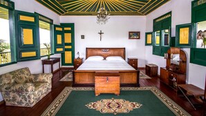 A room with a large bed, a wooden chest, a chair, and a chandelier. - Finca Hotel El Palmar (Montenegro)