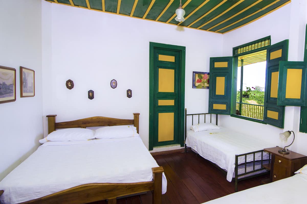 A room with two wooden beds, green doors, and a ceiling fan.
