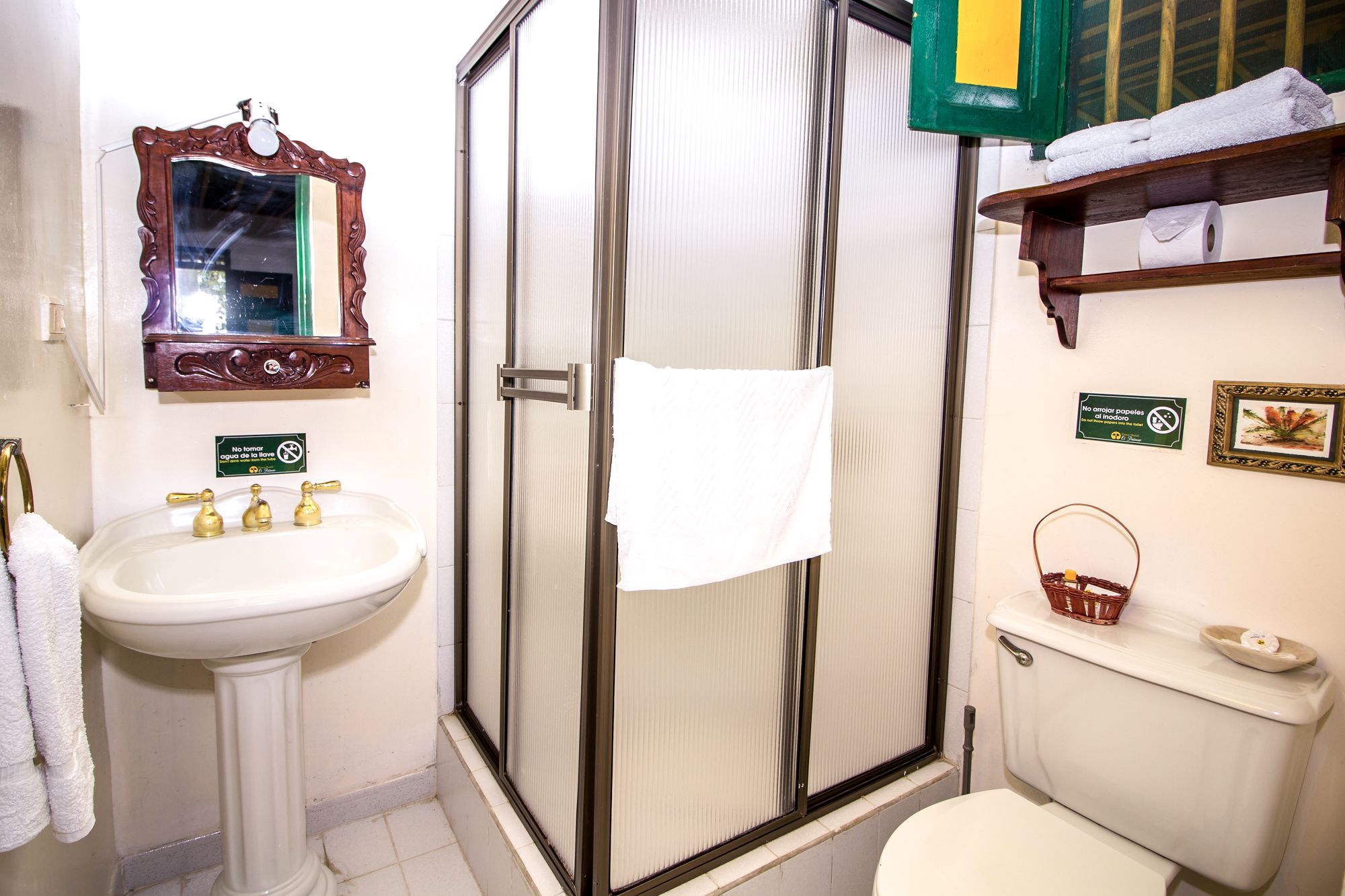 Een badkamer met een wastafel op voetstuk, een douchecabine, een toilet en een spiegel.