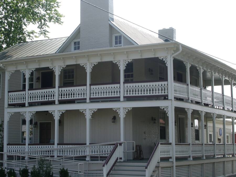 A two-story building with a balcony on each floor, featuring white railings and a central staircase.