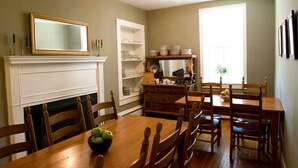 A dining room with a wooden table, chairs, a fireplace, a mirror, and a window. - Hopkins Ordinary Bed Breakfast and Ale Works (Sperryville)