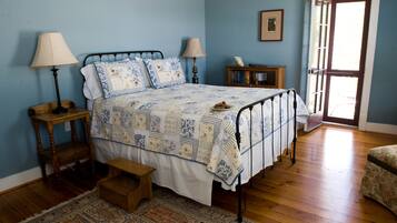 A bedroom with a bed, two bedside tables, a nightstand, a bench, a rug, and a door leading to another room.