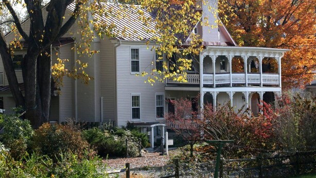 A two-story house with a porch and a small garden area. - Hopkins Ordinary Bed Breakfast and Ale Works (Sperryville)