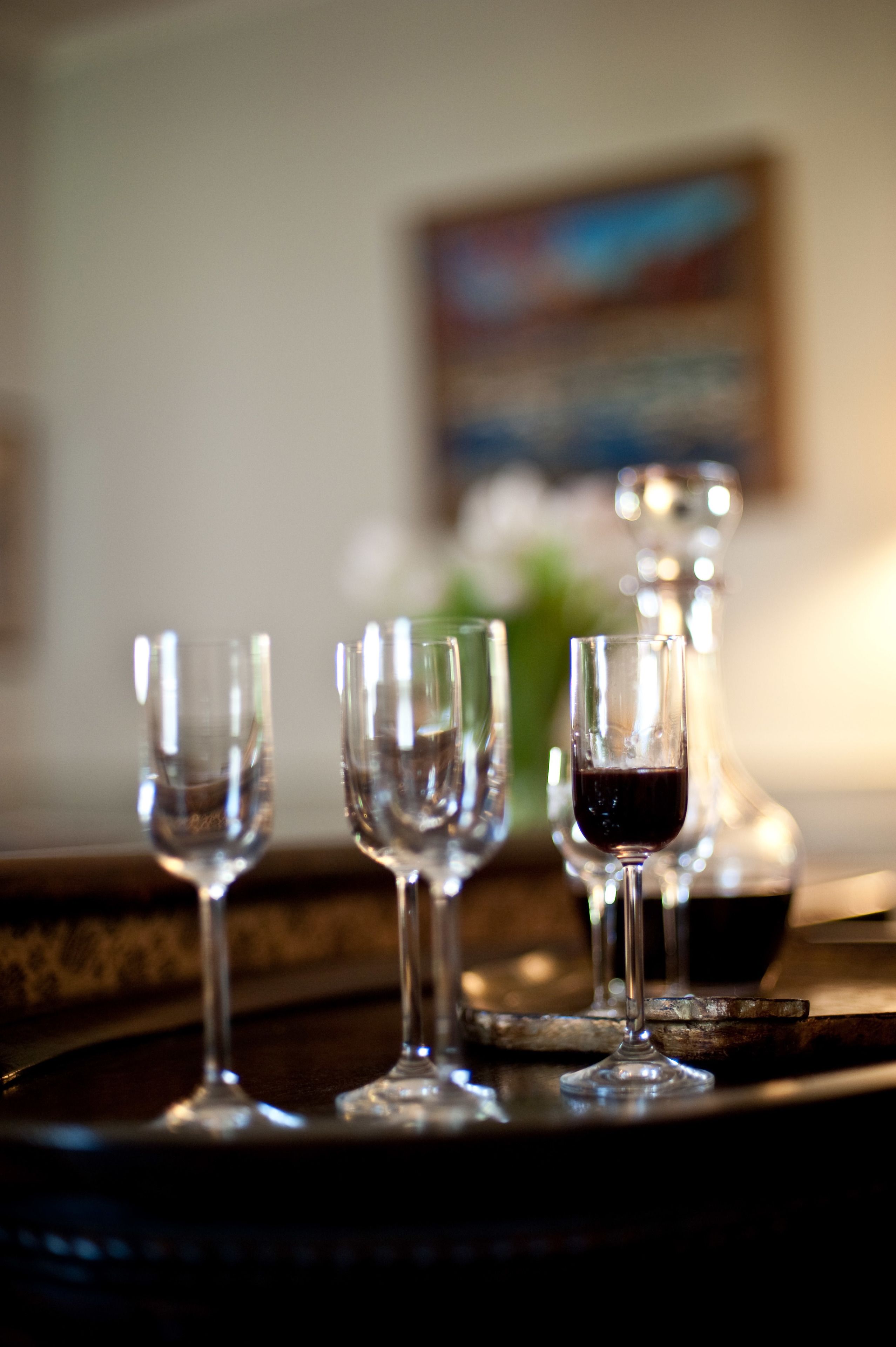 A tray with three empty wine glasses and one with red wine, set on a wooden surface.
