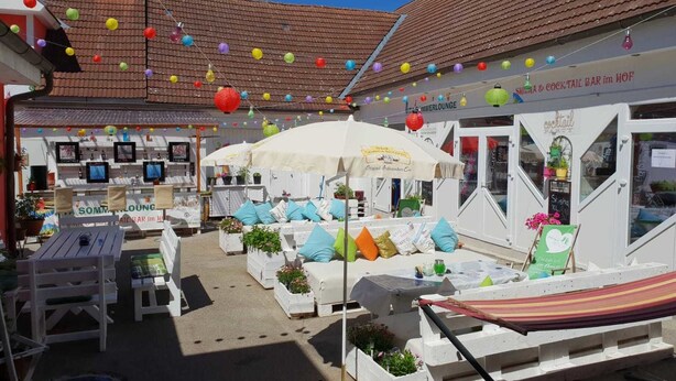 A courtyard with outdoor seating, umbrellas, and colorful decorations. - Vita Ristorante Gasthof (Rastenfeld)