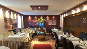 A restaurant with round tables, chairs, and a central decorative planter. - Vita Ristorante Gasthof (Rastenfeld)